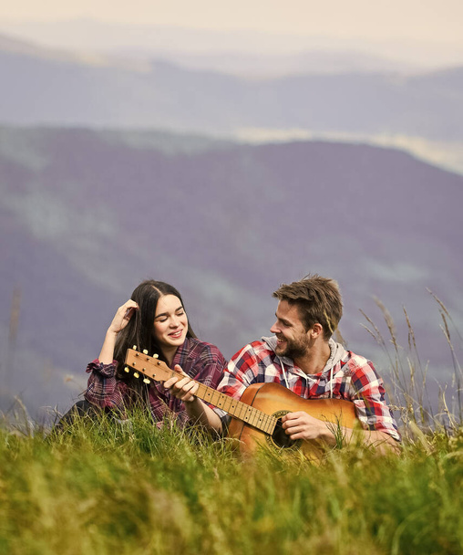 love song. couple in love spend free time together. western camping. hiking adventure. happy friends with guitar. friendship. campfire songs. country music. romantic date. men play guitar for girl - Foto, imagen