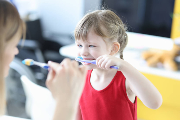 Pediatrician doctor teaching little girl to brush teeth - Photo, image