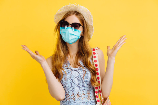 Young happy woman in medical protective mask and summer hat, in summer clothes, on isolated yellow background - Fotoğraf, Görsel