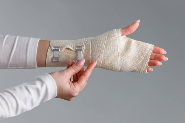 Gros plan de la femme enveloppant son poignet douloureux avec un bandage orthopédique élastique souple de soutien après un sport infructueux ou une blessure. Syndrome du canal carpien, arthrite, entorse au bras.  - Photo, image