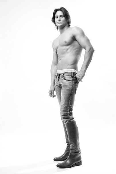 Fashion shot of a Young Man in a jeans and boots. Denuded torso - Foto, afbeelding