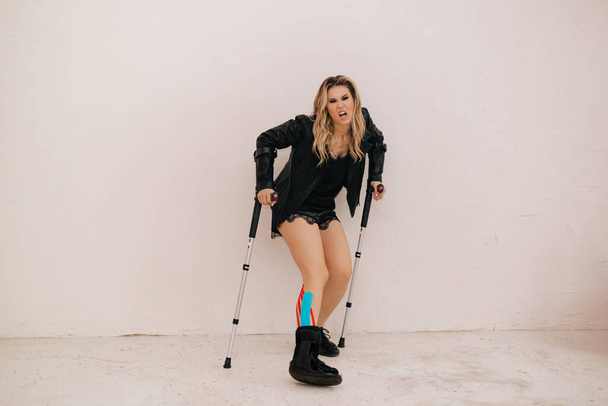 Woman on caste broke her leg while exercising. Accident insurance concept. Restoration of health with help of kineso tapes. - Zdjęcie, obraz