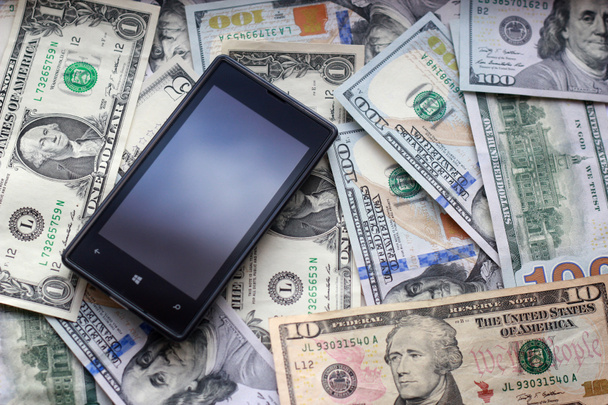 mobiele telefoon en dollar bank notes - Foto, afbeelding
