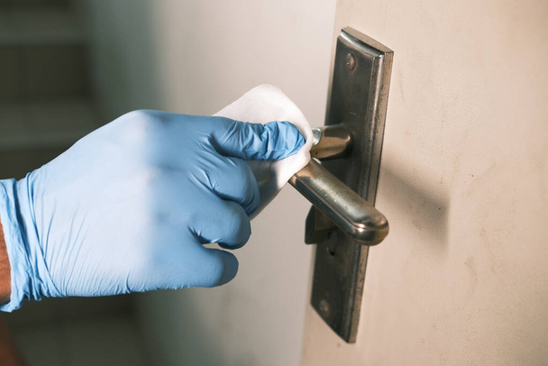 hand in gloves cleaning door knob with alcohol  - Foto, Imagen