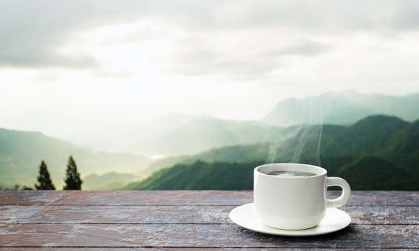 frisch gebrühter Kaffee oder Espresso in einen weißen Kaffeebecher. Heißer Kaffee im Becher auf der Tischplatte oder auf dem Holzbalkon. Morgenblick auf die Berge, Morgensonne. 3D-Rendering - Foto, Bild