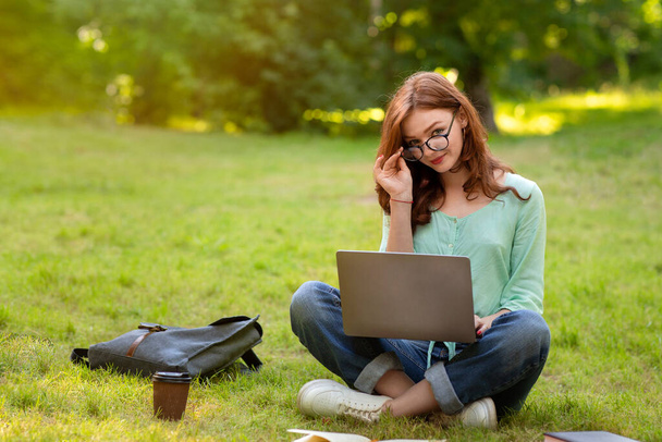 Portrait Of Cute Redhead Student Girl In Eyeglasses Studying With Laptop Outdoors - Foto, Imagem