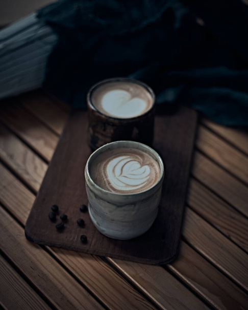 Selective focus cup of hot latte art coffee on wooden table,focus at white foa - Fotó, kép