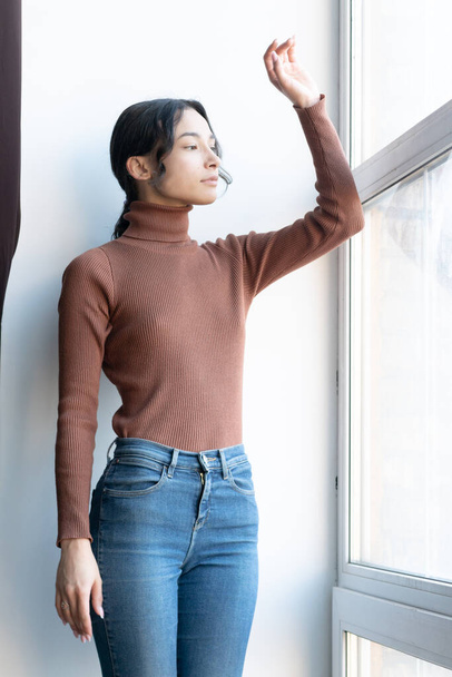 jonge mooie vrouwen poseren in bruine trui en jeans in de studio - Foto, afbeelding