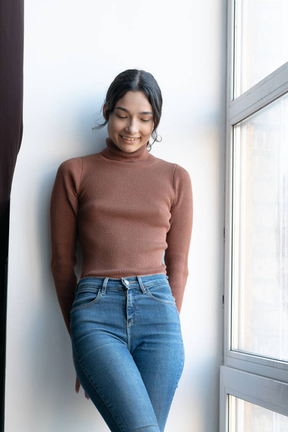 молоді красиві жінки позують в коричневому светрі і джинсах в студії
 - Фото, зображення