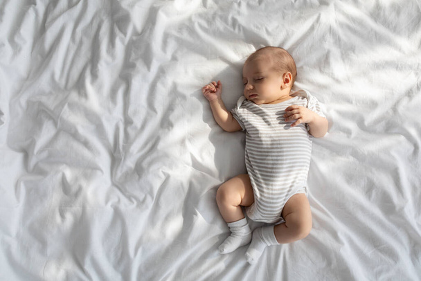 ベッドの中で眠っている愛らしい小さな新生児のショットのトップビュー - 写真・画像