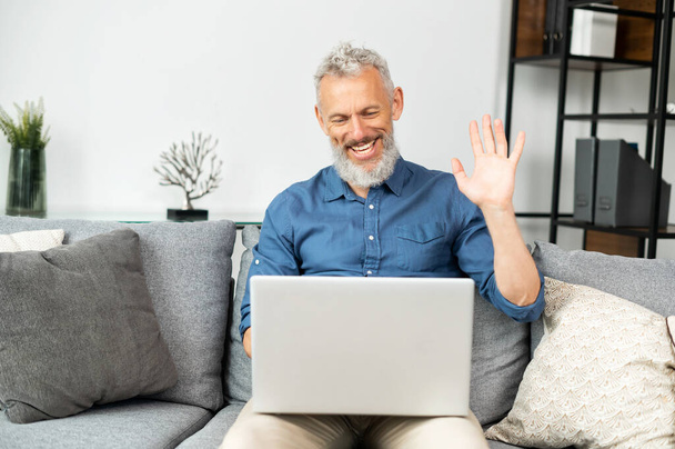 Contemporary cheerful senior man using laptop for video connection - Fotoğraf, Görsel