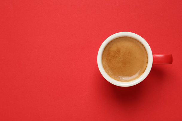 Cup of aromatic coffee on red background, top view. Space for text - Photo, Image