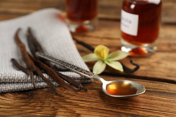 Aromatic vanilla extract and dry pods on wooden table - Photo, Image
