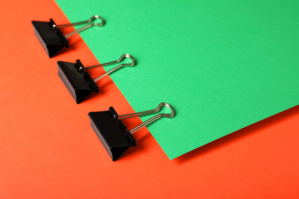 Black binder clips on color background. Stationery items - Photo, Image