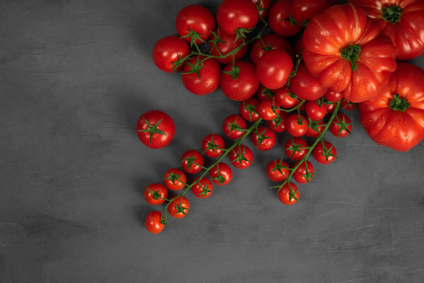 Tomates cerises sur la vigne sur fond de pierre sombre. Concept pour une alimentation saine. Image symbolique. Espace de copie. - Photo, image