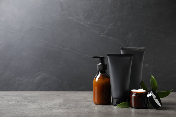 Facial cream and other men's cosmetic with green leaves on grey stone table. Mockup for design - Фото, зображення