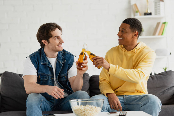boldog fiatal fajok közötti barátok csattogó üveg sör a nappaliban - Fotó, kép