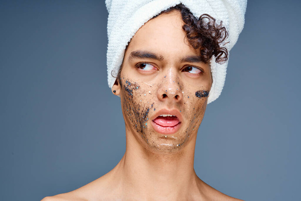 Cheerful guy with bare shoulders with a towel on his head, a black mask on his face - Photo, Image