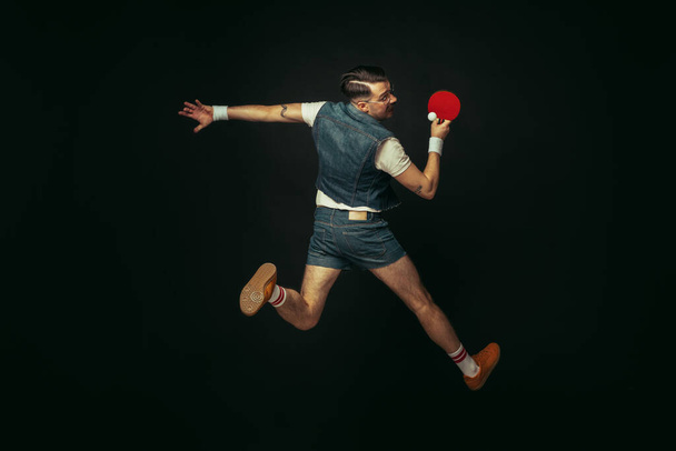 Young caucasian man playing tennis isolated on black studio background in retro style, action and motion concept - Fotó, kép