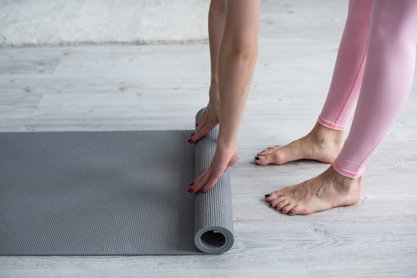 cropped view of barefoot woman unrolling yoga mat at home - Φωτογραφία, εικόνα