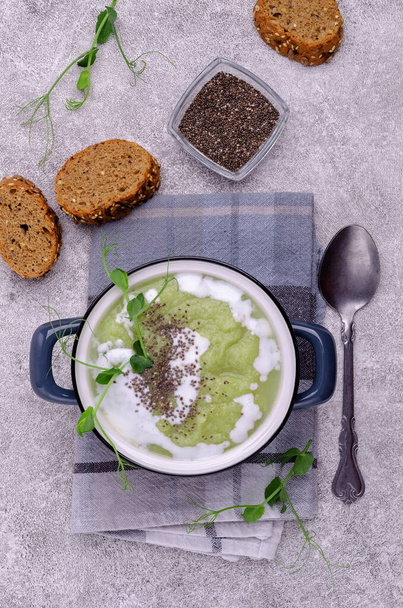 Товстий вершковий суп із зелених овочів з білим соусом, насінням чіа та паростками гороху на сірому фоні. Вибірковий фокус
. - Фото, зображення