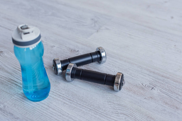 sports bottle with water near dumbbells on floor - Photo, image