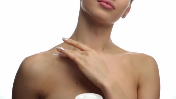 gedeeltelijk zicht van de vrouw die cosmetische crème op het op wit geïsoleerde sleutelbeen aanbrengt - Video