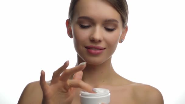 αργή κίνηση χαμογελαστή γυναίκα εφαρμογή κρέμα προσώπου σε λευκό - Πλάνα, βίντεο