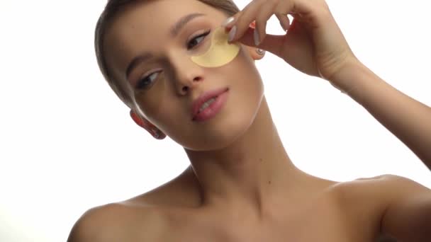 junge Frau mit nackten Schultern, die Augenklappe isoliert auf weiß aufträgt - Filmmaterial, Video
