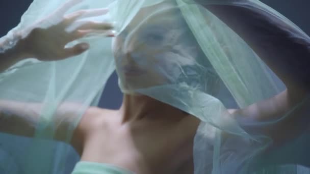 gezicht van jonge vrouw bedekt met chiffon doek op grijs  - Video