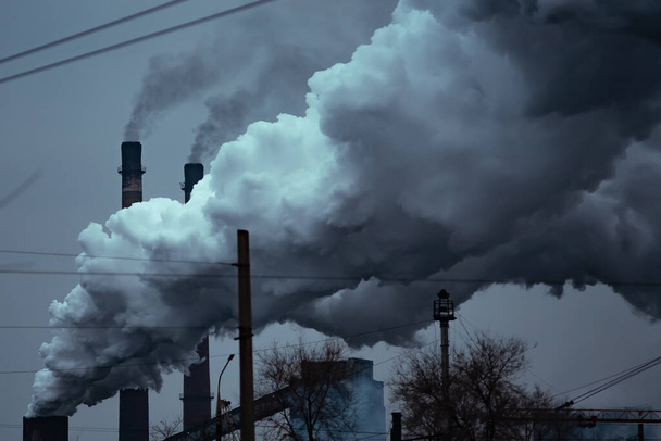 Fabriekspijp vervuilende lucht tegen, milieuproblemen, rook uit schoorstenen. - Foto, afbeelding