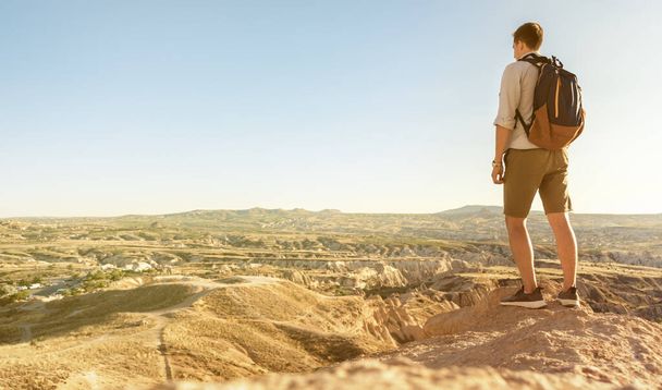 Back view young tourist with backpack standing on edge of valley at Cappadocia region, Turkey - Foto, Imagen