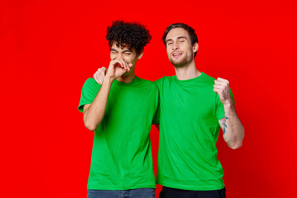 Два друга обнимаются в зеленых футболках - Фото, изображение