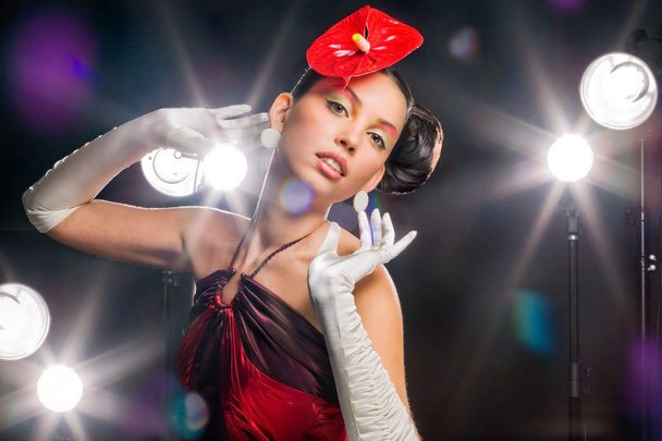 Beautiful girl with a red flower and in white gloves. On a background light shines - Foto, Imagem