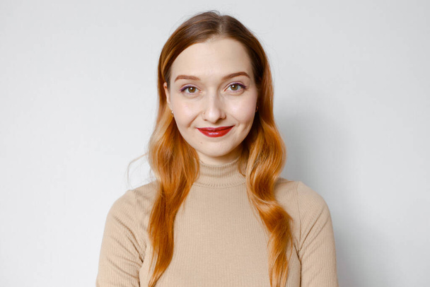 Portrait of a smiling red-haired woman. White background - Foto, afbeelding