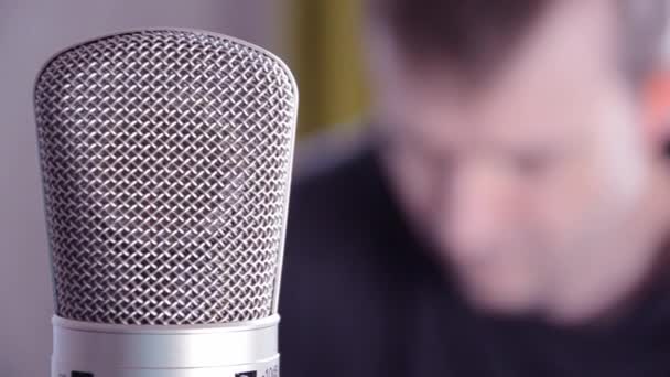 Селективный фокус конденсаторного микрофона на размытом фоне мужчин. Структура поверхности микрофона в студии. Домашние подкасты. - Кадры, видео