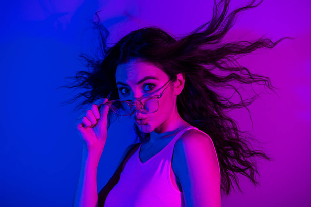 Profile photo of adorable girl kiss lips hand touch glasses look camera flying hair isolated on neon color background - Foto, Imagem