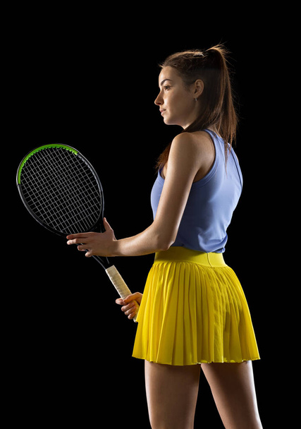 Young caucasian woman playing tennis isolated on black studio background in action and motion, sport concept - Foto, Imagem