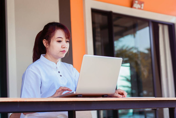 Азиатка работает на ноутбуке. Женщина, работающая с ноутбуком дома - Фото, изображение