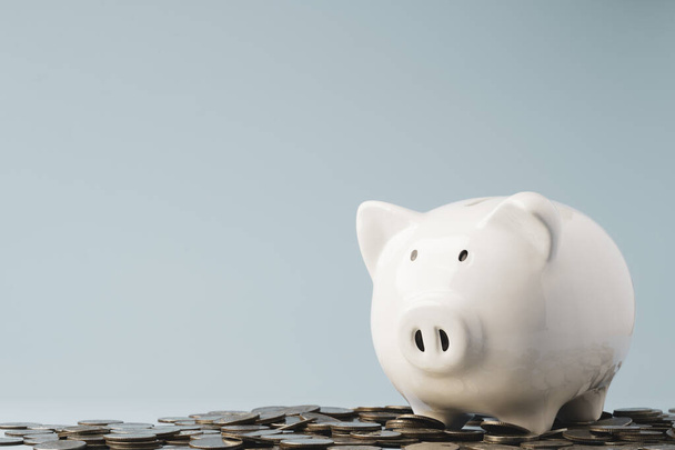 Λευκό piggy τράπεζα εξοικονόμηση σε σωρό των κερμάτων για την εξοικονόμηση χρημάτων και την έννοια της κατάθεσης. - Φωτογραφία, εικόνα