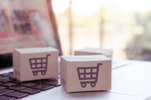 Online vásárlás. Kartondoboz egy bevásárlókosár logóval a laptop billentyűzetén. Bevásárlási szolgáltatás az interneten. házhozszállítás - Fotó, kép