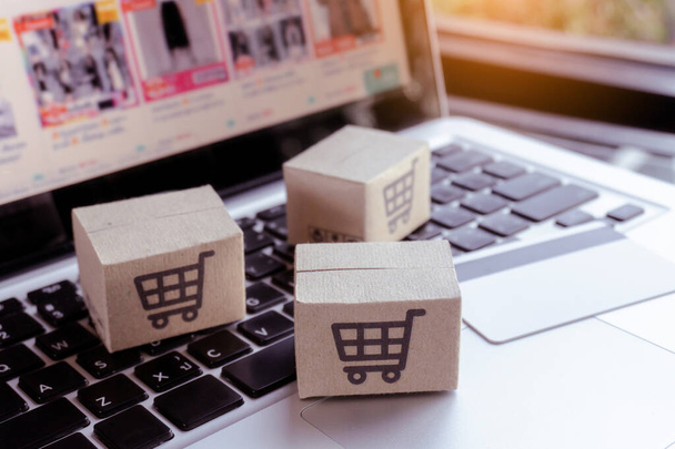 Online shopping. Credit card and cardboard box with a shopping cart logo on laptop keyboard. Shopping service on The online web. offers home deliver - Fotografie, Obrázek