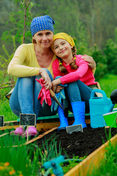 Gardening, planting - girl helping mother in the garden - Photo, Image