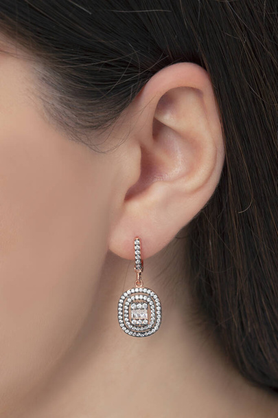 Srebrne wiszące kolczyki przymocowane do ucha zadbanej damy. Wizerunek biżuterii, który można wykorzystać w sprzedaży w e-commerce. - Zdjęcie, obraz