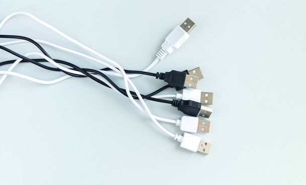 Ένα μάτσο διαφορετικά καλώδια USB για φορτιστή ή συσκευές σύνδεσης πάνω όψη σε γκρι φόντο - Φωτογραφία, εικόνα
