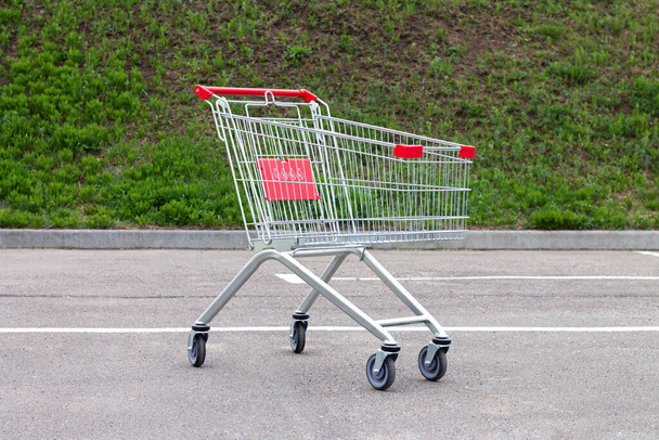 Empty red shopping cart or trolley on suppermarket parking - Foto, Bild