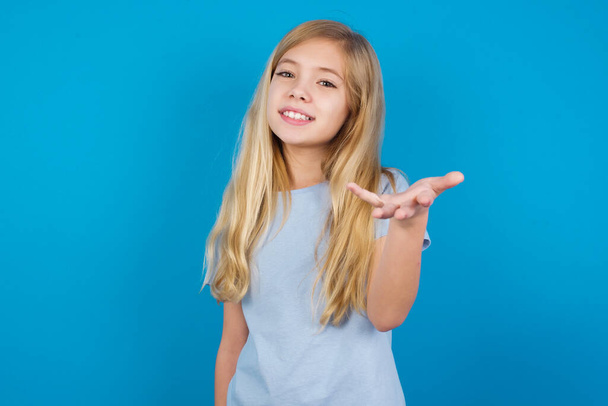 beautiful caucasian girl wearing blue t-shirt  smiling friendly offering something with open hand or handshake as greeting and welcoming. Successful business. - Foto, immagini