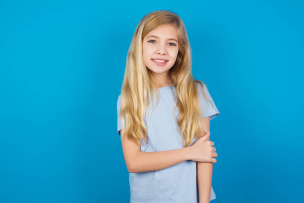 όμορφη καυκάσια κοπέλα φορώντας μπλε μπλουζάκι γελώντας απομονωμένη στο μπλε  - Φωτογραφία, εικόνα