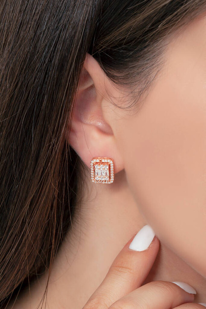 Boucles d'oreilles pendantes en argent attachées à l'oreille d'une dame toilettée. Image de bijoux qui peut être utilisé dans les ventes e-commerce. - Photo, image