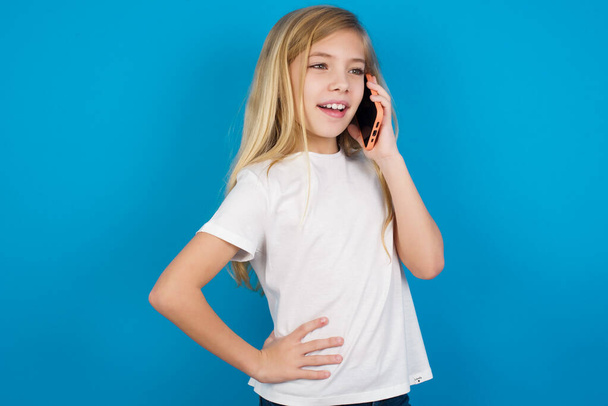 Portrait of successful joyful  beautiful caucasian girl wearing t-shirt    talking on mobile phone with friend. Lifestyle and communication concept - Foto, Bild